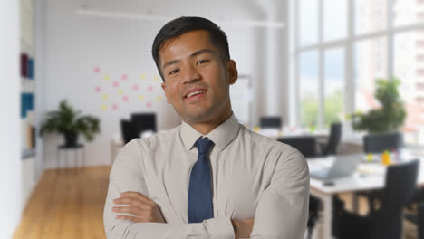 Portrait-Of-Smiling-Businessman-Wearing-Collar-And-Tie-Standing-In-Modern-Open-Plan-Office